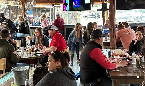 A bunch of folks looking like they are having a great time over dinner.